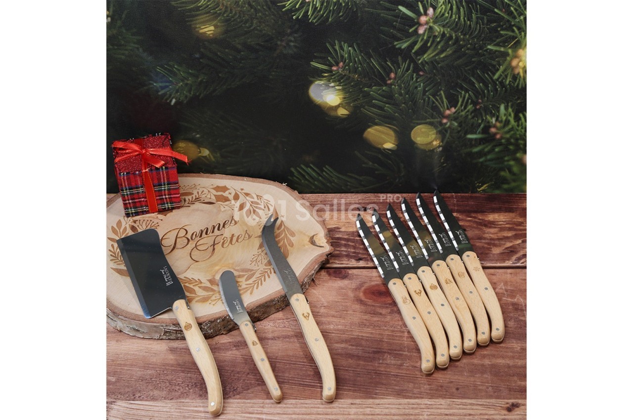 Plateau en bois gravé ’Bonnes Fêtes’ avec couteaux à manche clair, hachette et décorations de Noël en arrière-plan.