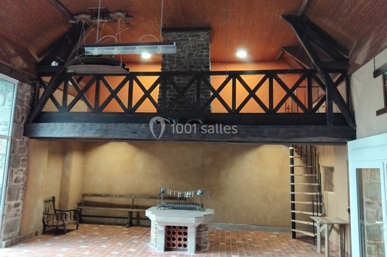 Salle avec mezzanine en bois, mur en pierre, plafond en bois, barbecue intérieur et sol en carrelage.
