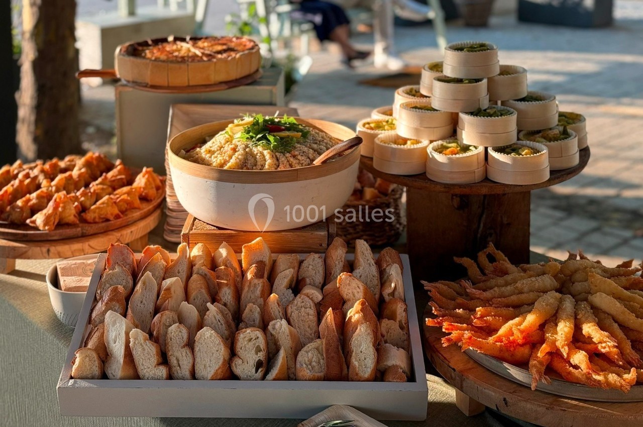 Buffet en plein air avec pain, houmous, beignets de crevettes et bouchées servies dans des paniers en bambou.