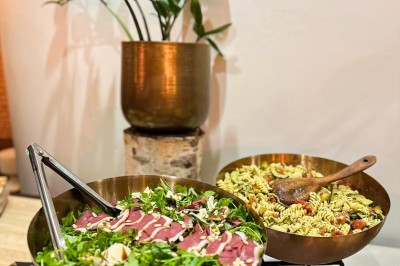 Miniature Traiteur Paris 20 (Paris) - Atelier des Sens #28 Table garnie de plats variés, incluant charcuterie et fromages, installée en extérieur près d'un plan d'eau.