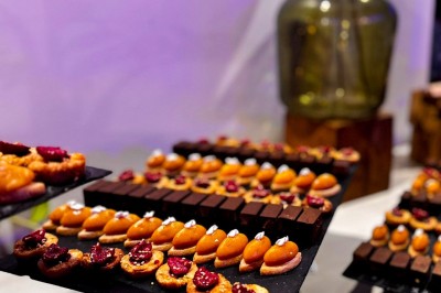 Miniature Traiteur Paris 20 (Paris) - Atelier des Sens #44 Table garnie de plats variés, incluant charcuterie et fromages, installée en extérieur près d'un plan d'eau.
