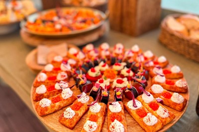 Miniature Traiteur Paris 20 (Paris) - Atelier des Sens #53 Table garnie de plats variés, incluant charcuterie et fromages, installée en extérieur près d'un plan d'eau.