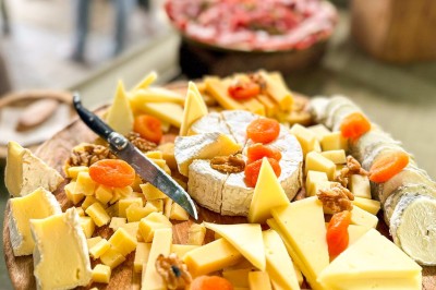 Miniature Traiteur Paris 20 (Paris) - Atelier des Sens #45 Table garnie de plats variés, incluant charcuterie et fromages, installée en extérieur près d'un plan d'eau.