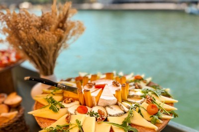 Miniature Traiteur Paris 20 (Paris) - Atelier des Sens #57 Table garnie de plats variés, incluant charcuterie et fromages, installée en extérieur près d'un plan d'eau.
