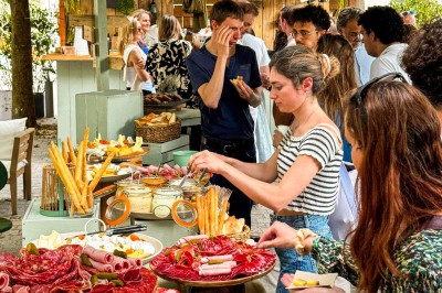 Miniature Traiteur Paris 20 (Paris) - Atelier des Sens #22 Table garnie de plats variés, incluant charcuterie et fromages, installée en extérieur près d'un plan d'eau.