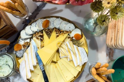 Miniature Traiteur Paris 20 (Paris) - Atelier des Sens #52 Table garnie de plats variés, incluant charcuterie et fromages, installée en extérieur près d'un plan d'eau.
