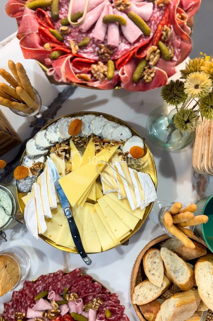 Plateau de fromages variés avec charcuteries, pain, gressins et décorations sur une table.