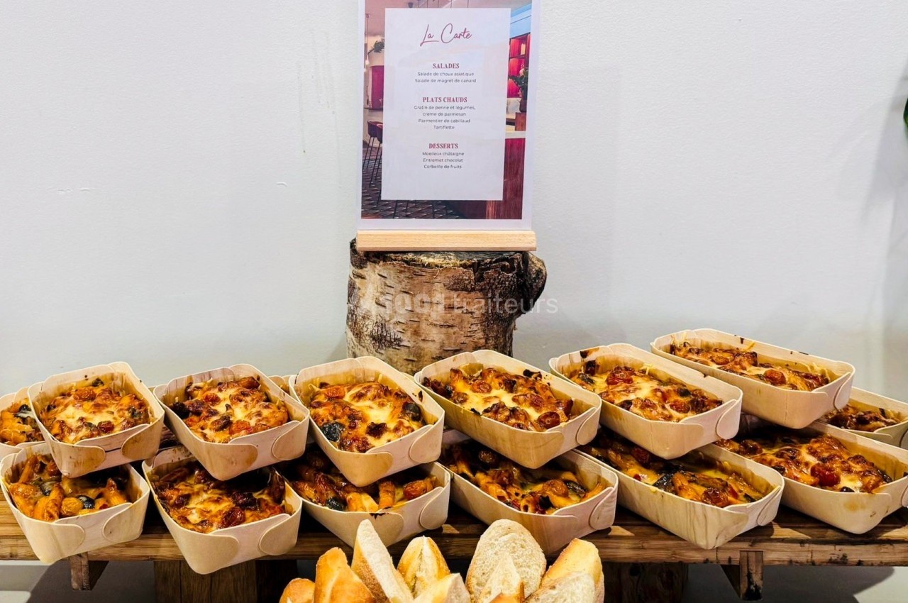 Plateau de quiches individuelles dorées dans des barquettes en bois, disposées sur une table avec des tranches de pain.