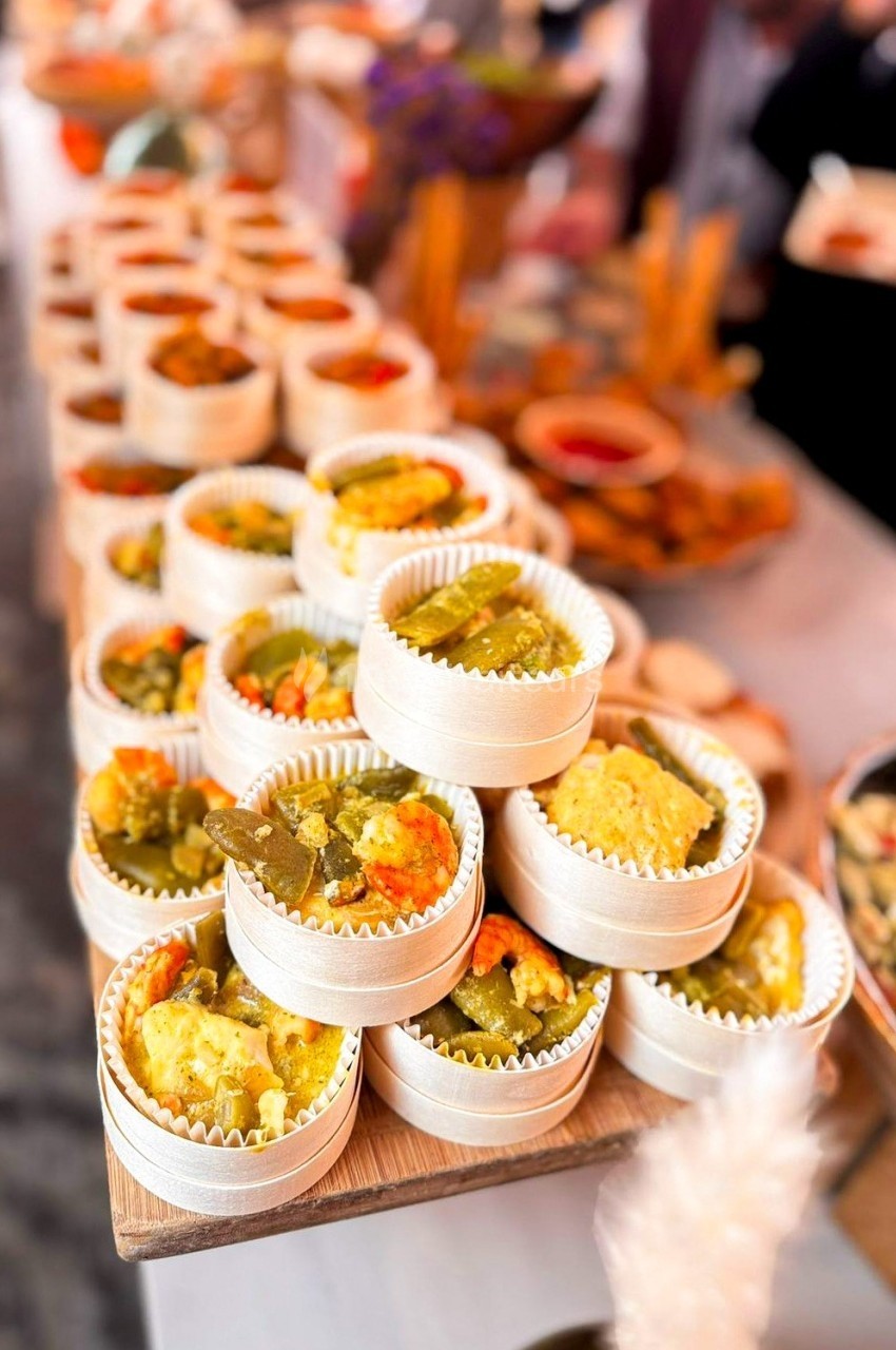 Assortiment de petits plats en barquettes individuelles contenant des légumes colorés, disposés sur une table de buffet.