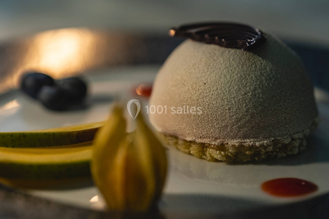 Dessert élégant en dôme avec glaçage beige, décoré de chocolat, fruits frais et touches de coulis rouge.