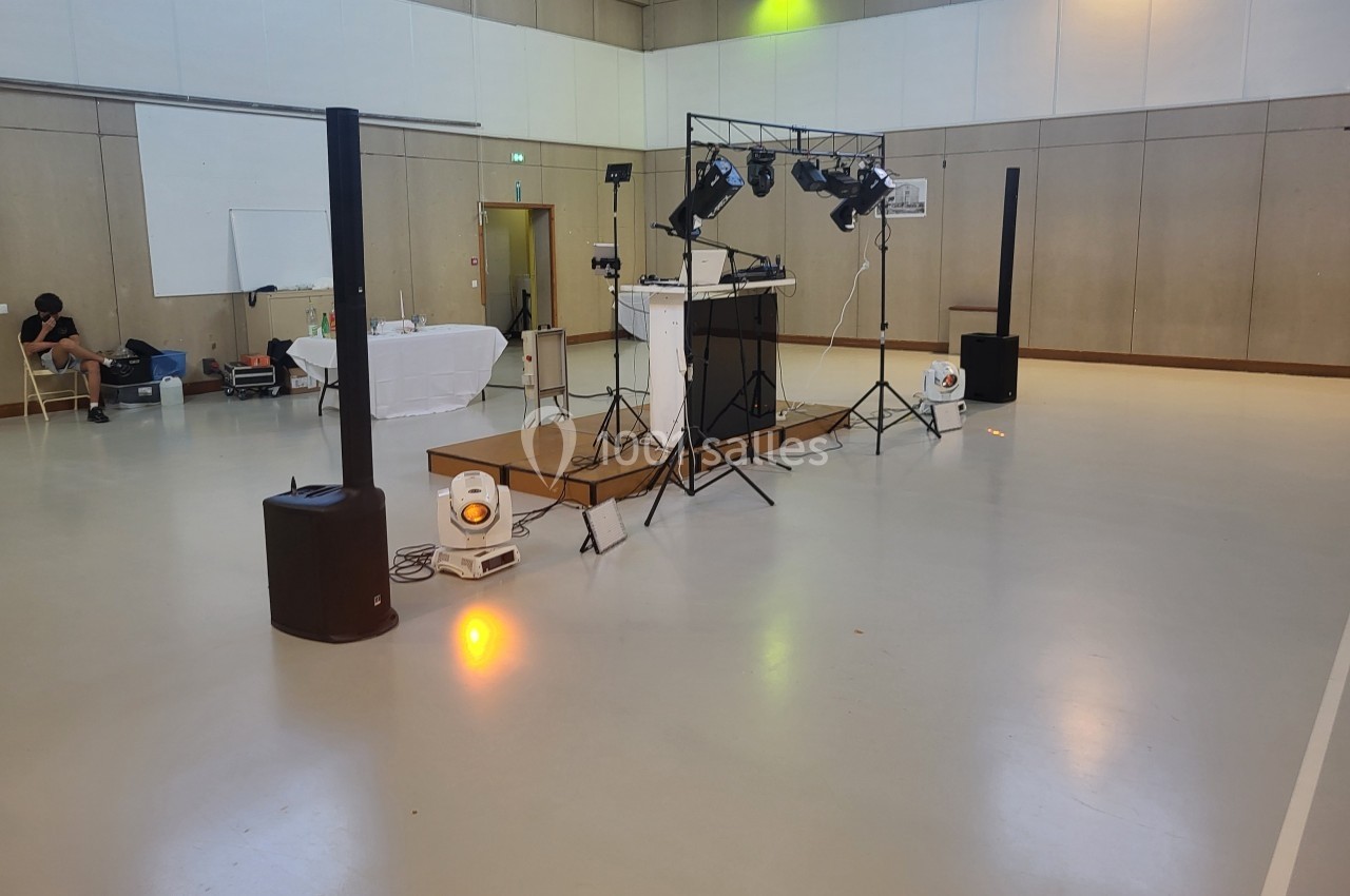 Installation de matériel de sonorisation et d'éclairage dans une salle polyvalente vide.
