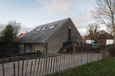 Façade d'une maison orange à trois étages avec toit en tuiles, entourée de bâtiments en briques et d'une cour pavée.