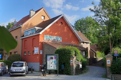 Façade d'une maison orange à trois étages avec toit en tuiles, entourée de bâtiments en briques et d'une cour pavée.