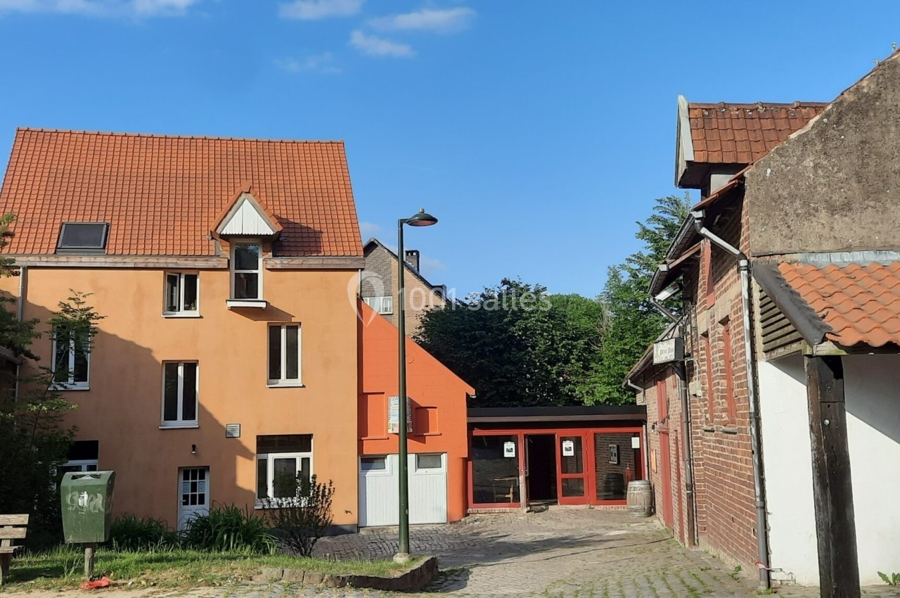 Maisons en briques et crépi orange avec toits en tuiles, bordant une ruelle pavée sous un ciel bleu.