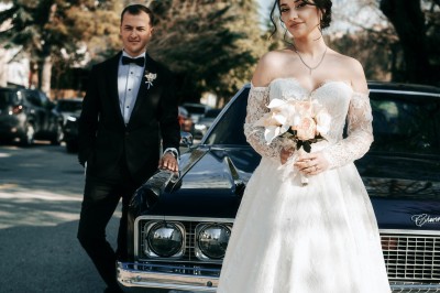 Miniature Germain Photo Reporter #4 Une femme en robe de mariée tient un bouquet de tournesols près d'une voiture ancienne rouge, de nuit.