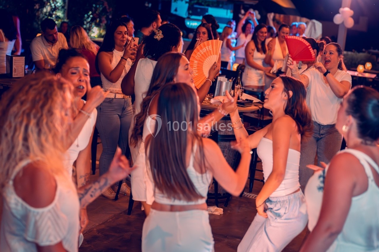 Groupe de femmes en tenue blanche dansant et s'amusant lors d'une soirée en extérieur.