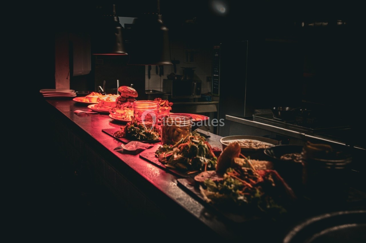 Plats variés disposés sur un comptoir dans une cuisine faiblement éclairée.