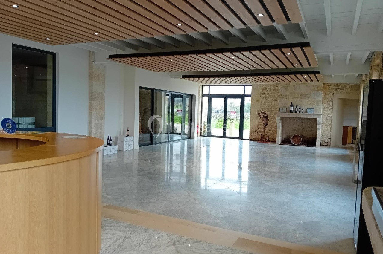 Espace intérieur lumineux avec sol en marbre, comptoir en bois, murs en pierre et grandes baies vitrées donnant sur l…
