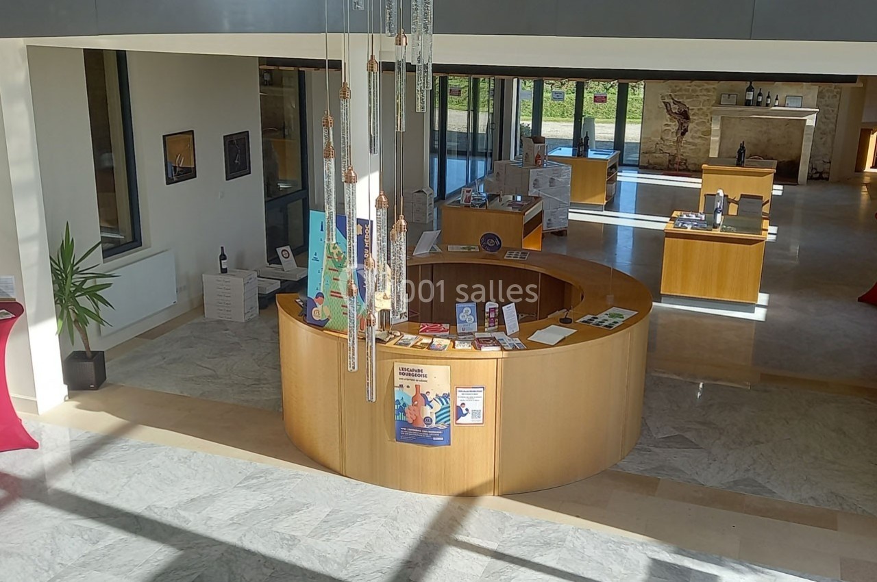 Accueil circulaire en bois dans un hall lumineux, avec brochures et affiches disposées sur le comptoir.