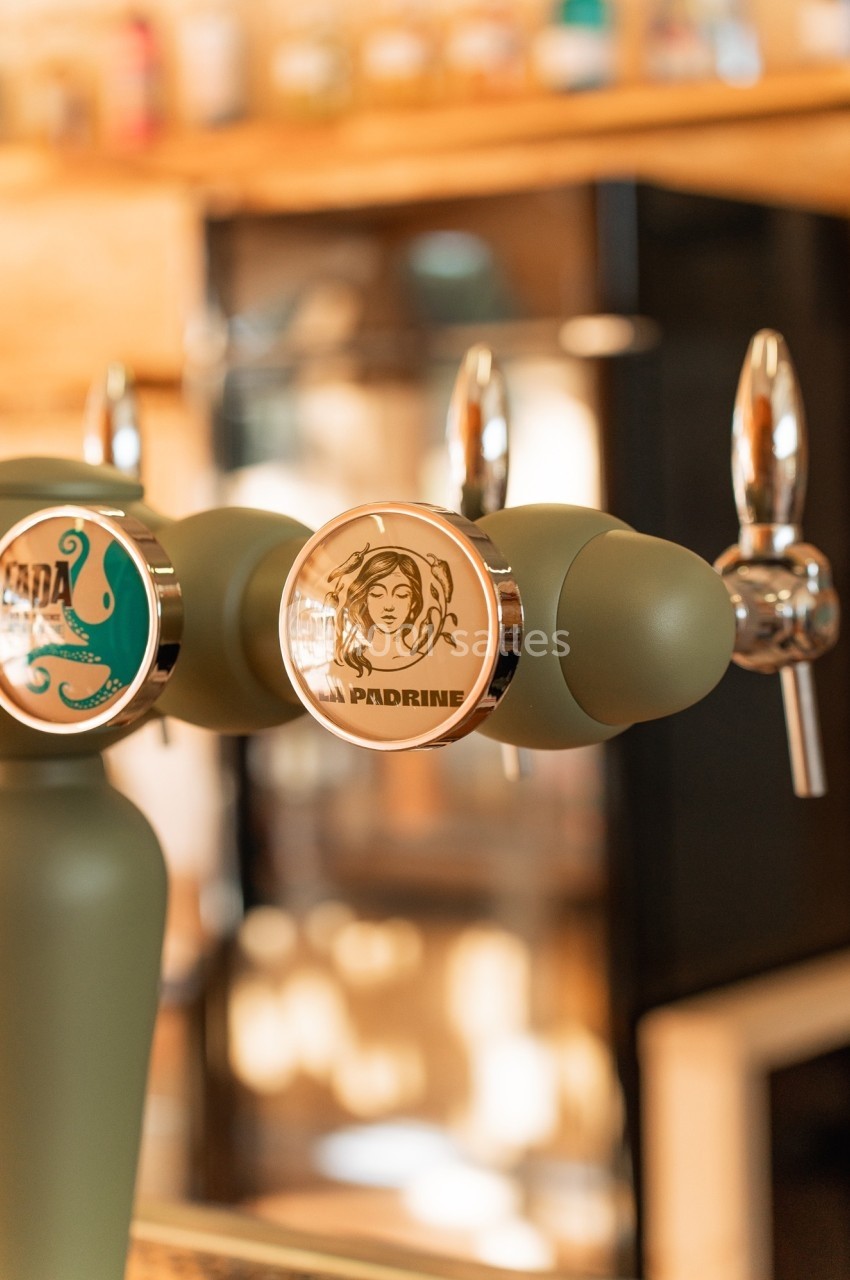 Deux tireuses à bière avec des logos distincts, installées sur un comptoir en bois dans un bar.