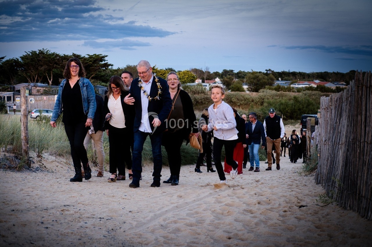 Un groupe de personnes marche sur un sentier sablonneux entouré de dunes et de végétation.