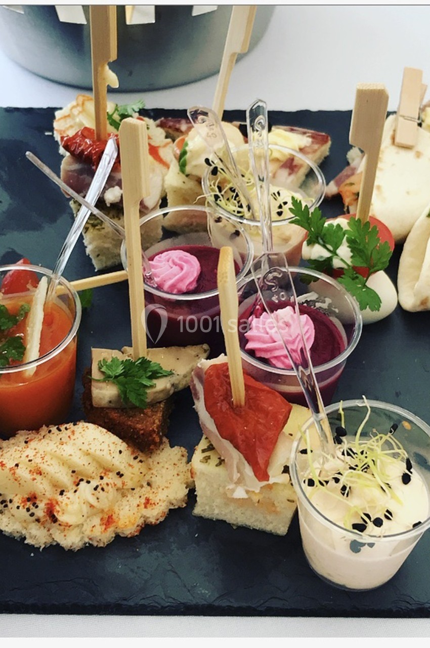 Plateau de bouchées apéritives variées comprenant verrines, toasts, wraps et décorations culinaires.