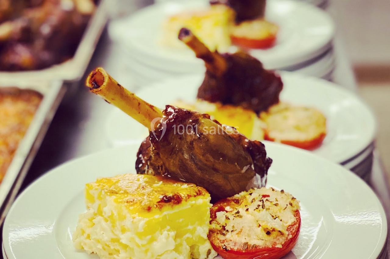 Assiette de jarret d'agneau braisé avec gratin dauphinois et tomate provençale, servie en file sur des assiettes blanches.