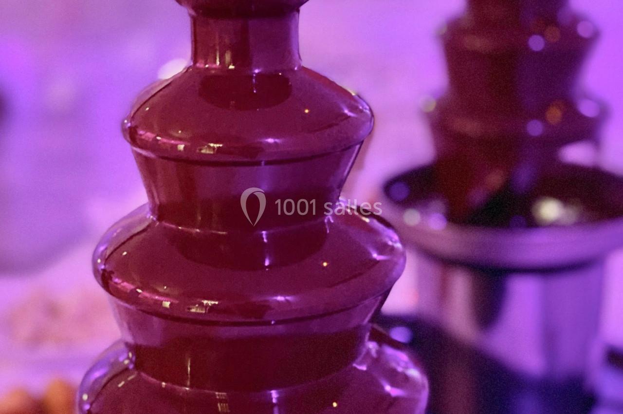 Fontaine à chocolat en fonctionnement avec plusieurs étages, entourée d'une ambiance lumineuse violette.