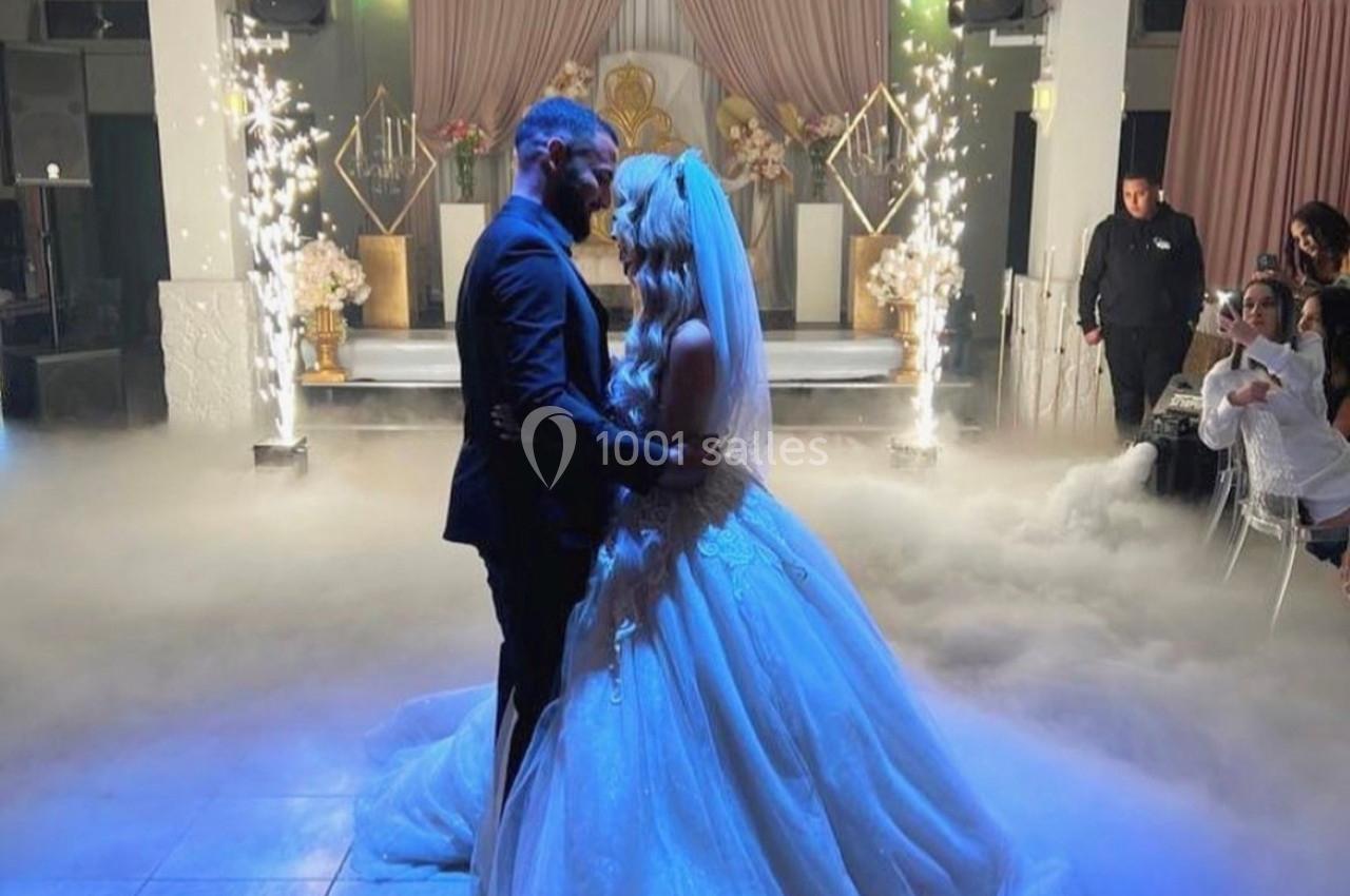 Un couple de mariés danse sous des lumières scintillantes et une ambiance de fumée sur une piste de réception.