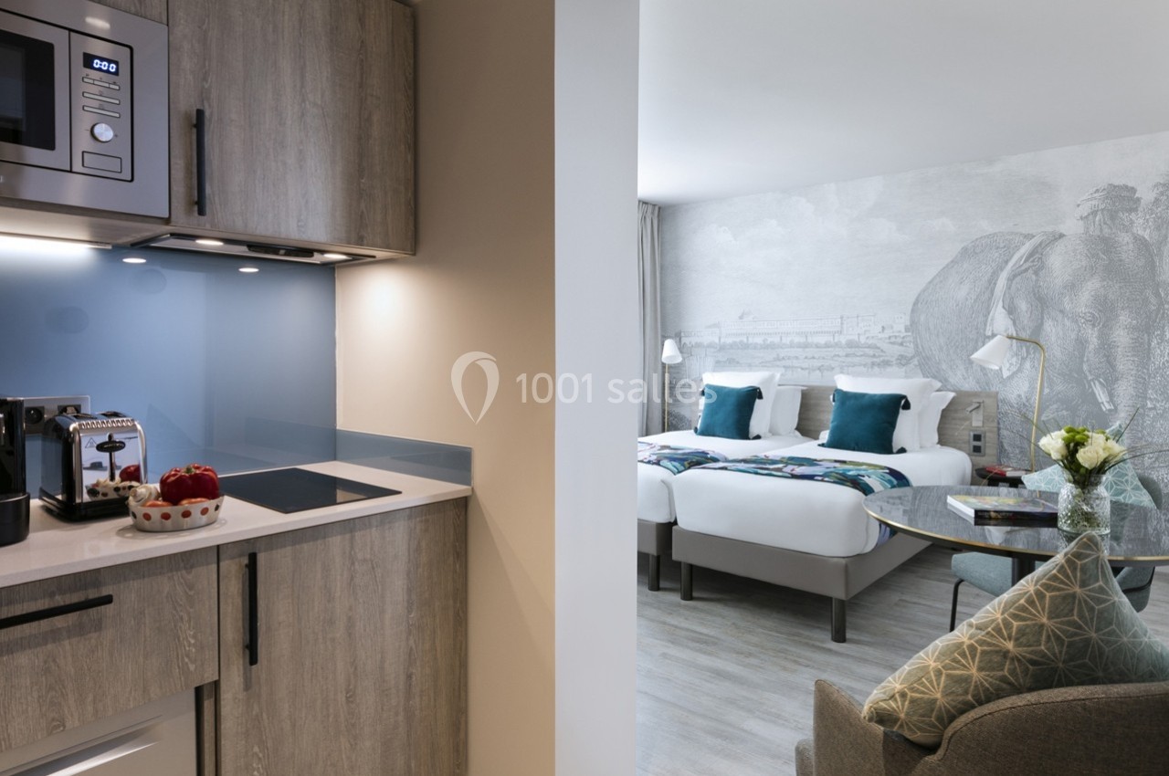 Cuisine équipée moderne et coin nuit avec deux lits simples dans une chambre lumineuse et décorée avec soin.