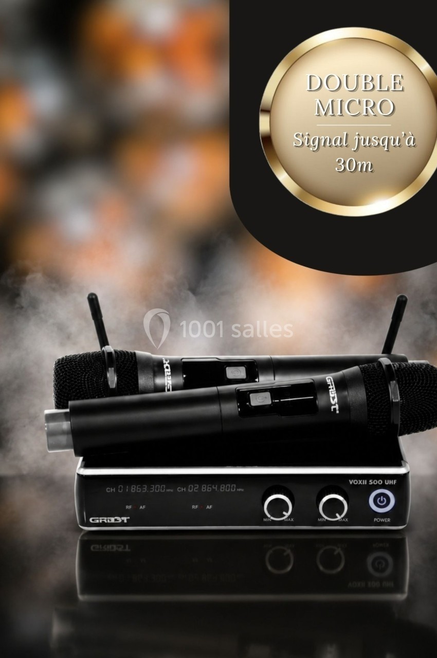 Deux microphones sans fil noirs posés sur un récepteur audio, avec un fond flou et une mention de portée jusqu'à 30 m.