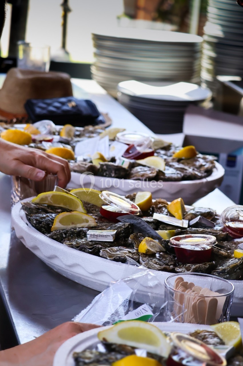Plateaux d'huîtres garnis de quartiers de citron et de sauces, disposés sur un comptoir en extérieur.