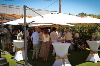 Miniature Location salle Toulouse (Haute-Garonne) - La Cantine d'Horace #17 Terrasse extérieure avec tables et chaises sous des parasols, entourée de verdure et située près d'un bâtiment industriel.
