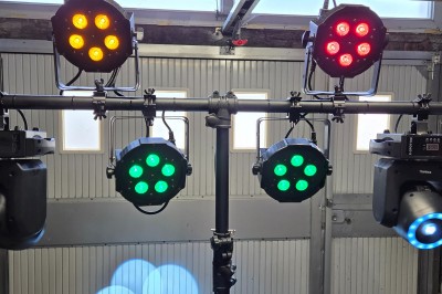 Miniature Jeux de Lumières Projecteurs LED colorés montés sur une structure métallique dans un garage, prêts pour une utilisation événementielle.
