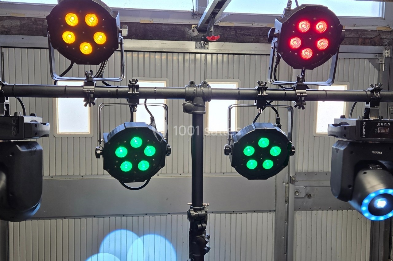Projecteurs LED colorés montés sur une structure métallique dans un garage, prêts pour une utilisation événementielle.