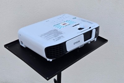 Miniature Vidéo Projecteur Projecteurs LED colorés montés sur une structure métallique dans un garage, prêts pour une utilisation événementielle.