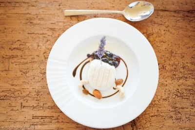 Tartare de saumon garni de jeunes pousses et entouré de filet de sauce balsamique sur une assiette blanche.