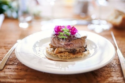 Tartare de saumon garni de jeunes pousses et entouré de filet de sauce balsamique sur une assiette blanche.