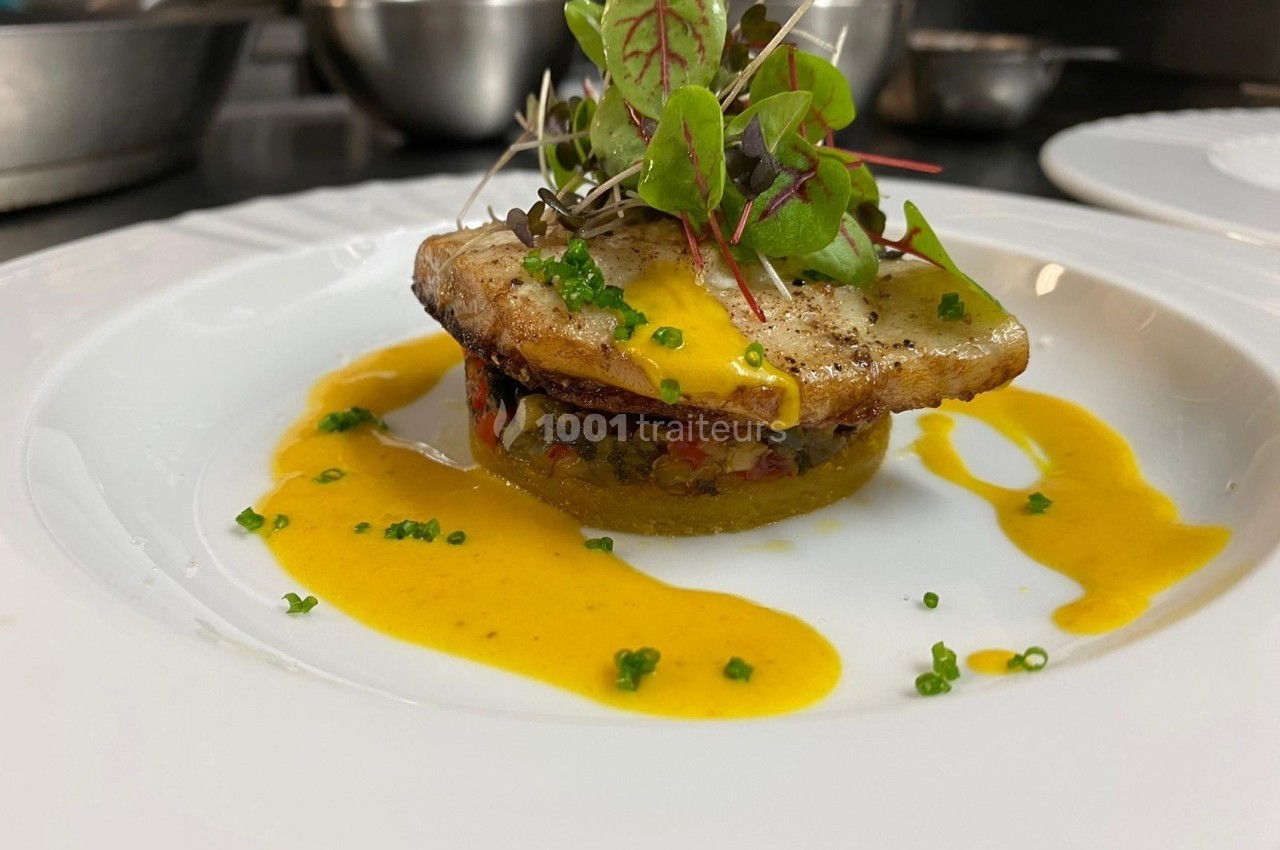 Plat gastronomique composé de poisson grillé, légumes en base, sauce jaune et micro-pousses en garniture.
