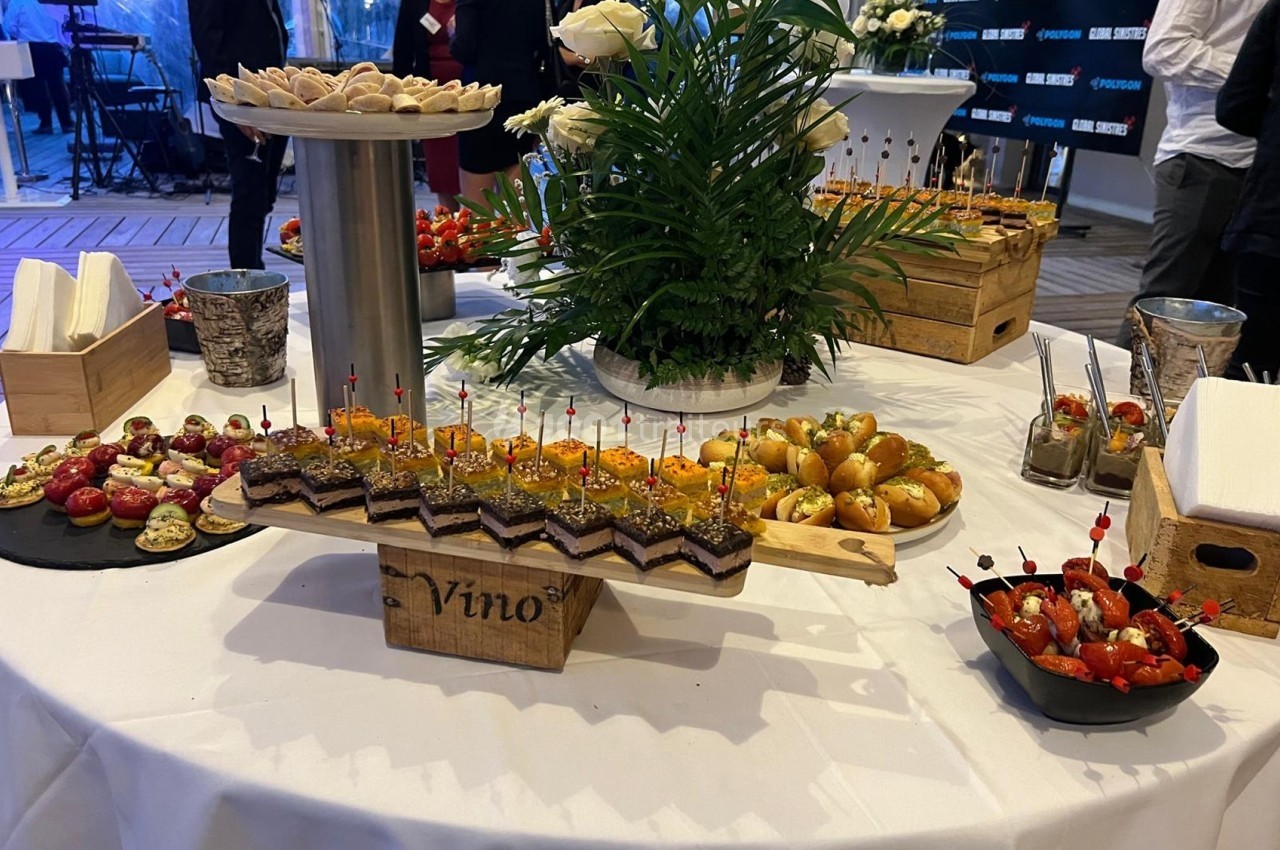 Table garnie de divers amuse-bouches, incluant canapés, verrines et petits pains, lors d'un événement.