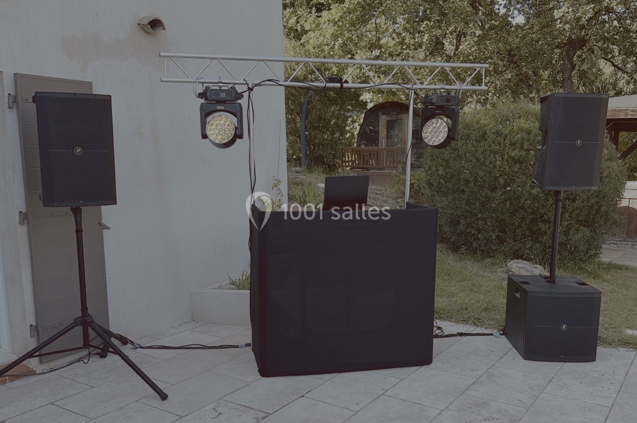 Installation de matériel de sonorisation et éclairage en extérieur, comprenant enceintes, projecteurs et table de mixage.