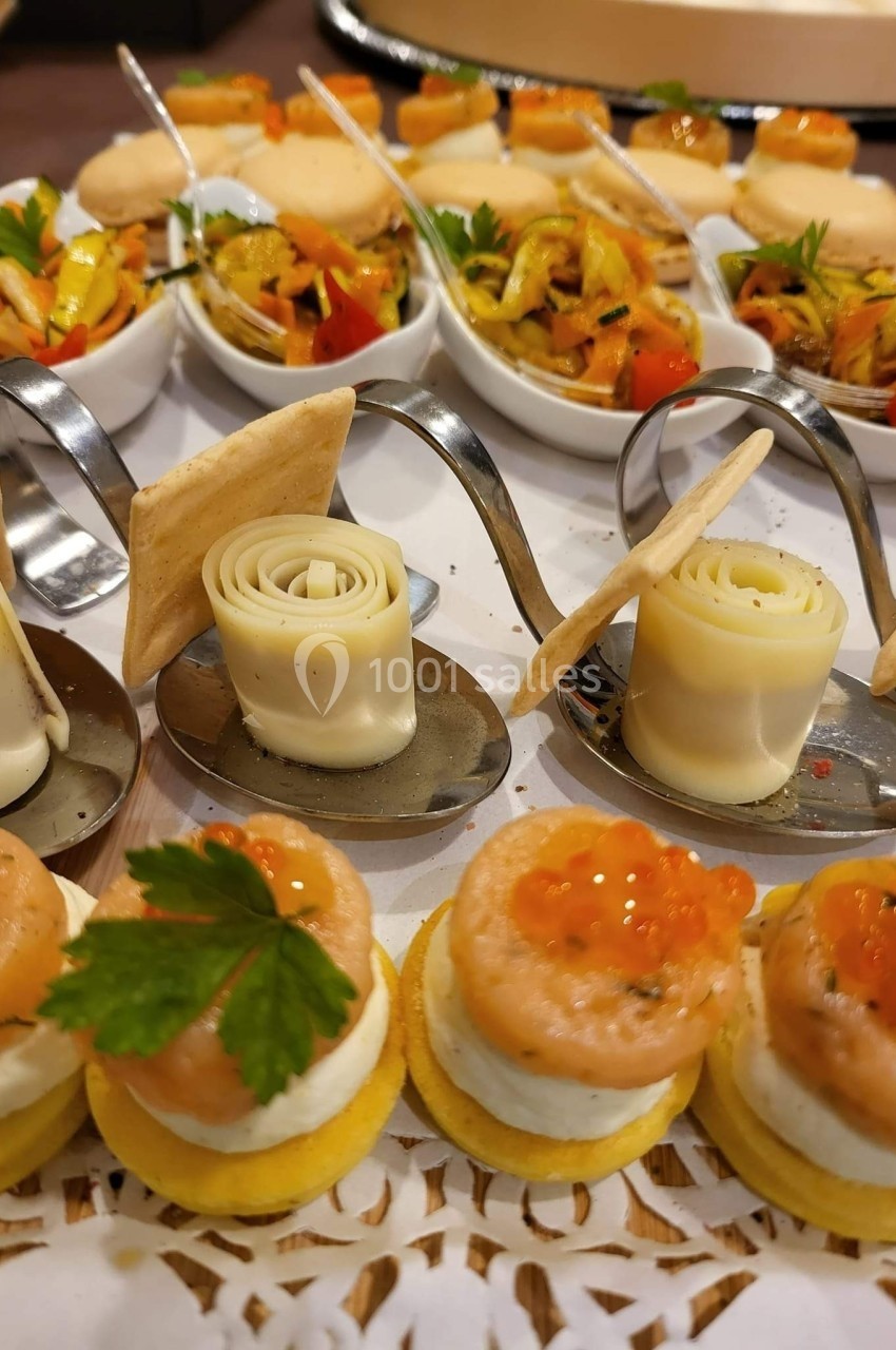 Assortiment de bouchées apéritives comprenant roulés de fromage, verrines de légumes et canapés au saumon.