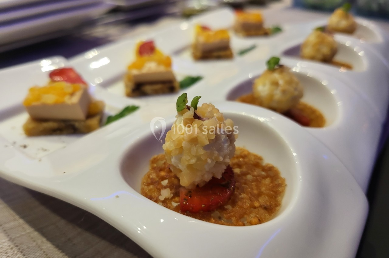 Assortiment de bouchées gastronomiques présentées sur un plateau blanc, avec des garnitures variées.