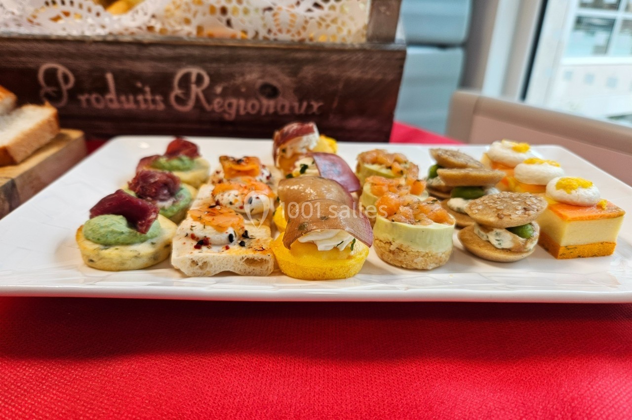 Assortiment de canapés variés présentés sur une assiette blanche, posé sur une nappe rouge.