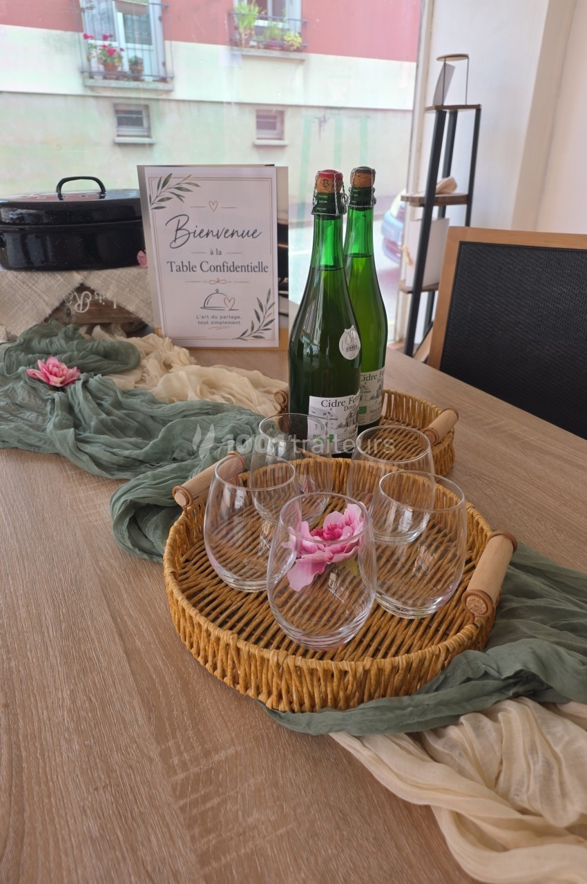 Table décorée avec des verres, des bouteilles d'eau, un panier en osier et un chemin de table orné de fleurs.