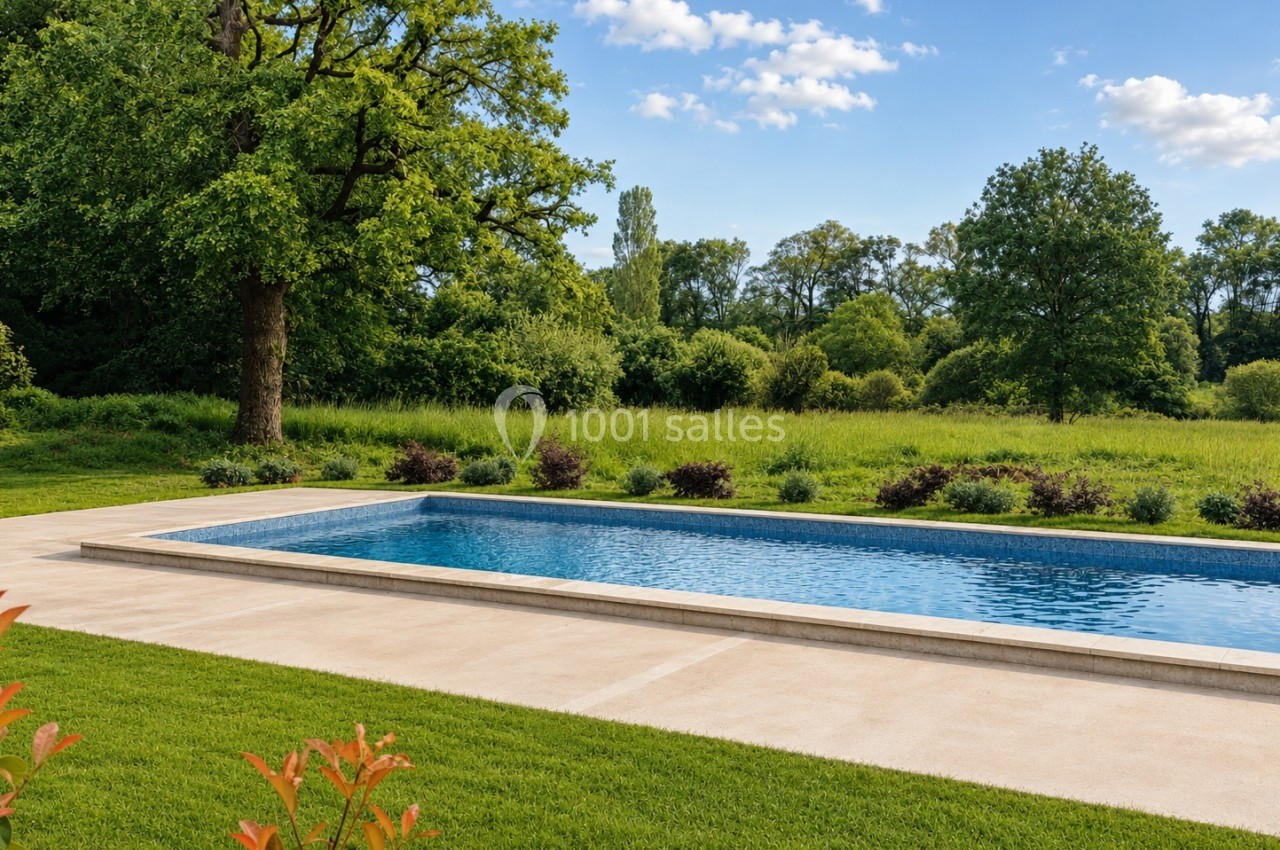 Piscine rectangulaire entourée de pelouse et d'arbustes, avec un paysage naturel verdoyant en arrière-plan.