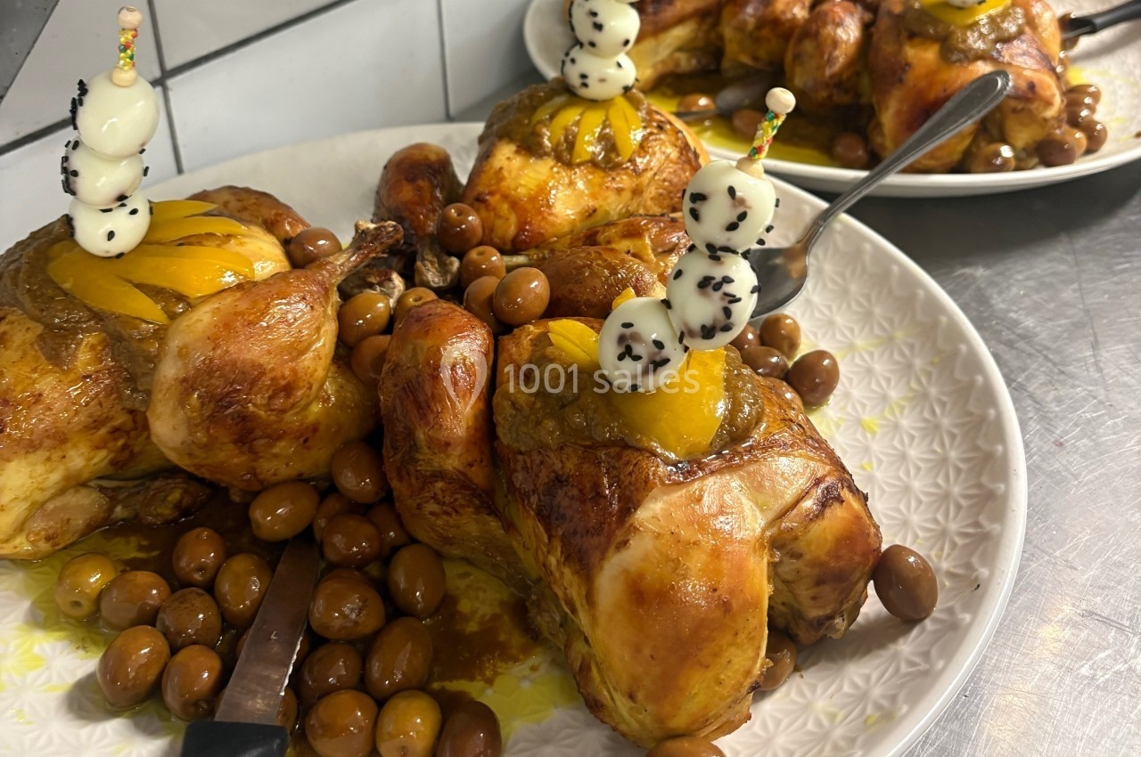 Poulets rôtis garnis de fruits et accompagnés d'olives, présentés sur une assiette blanche.