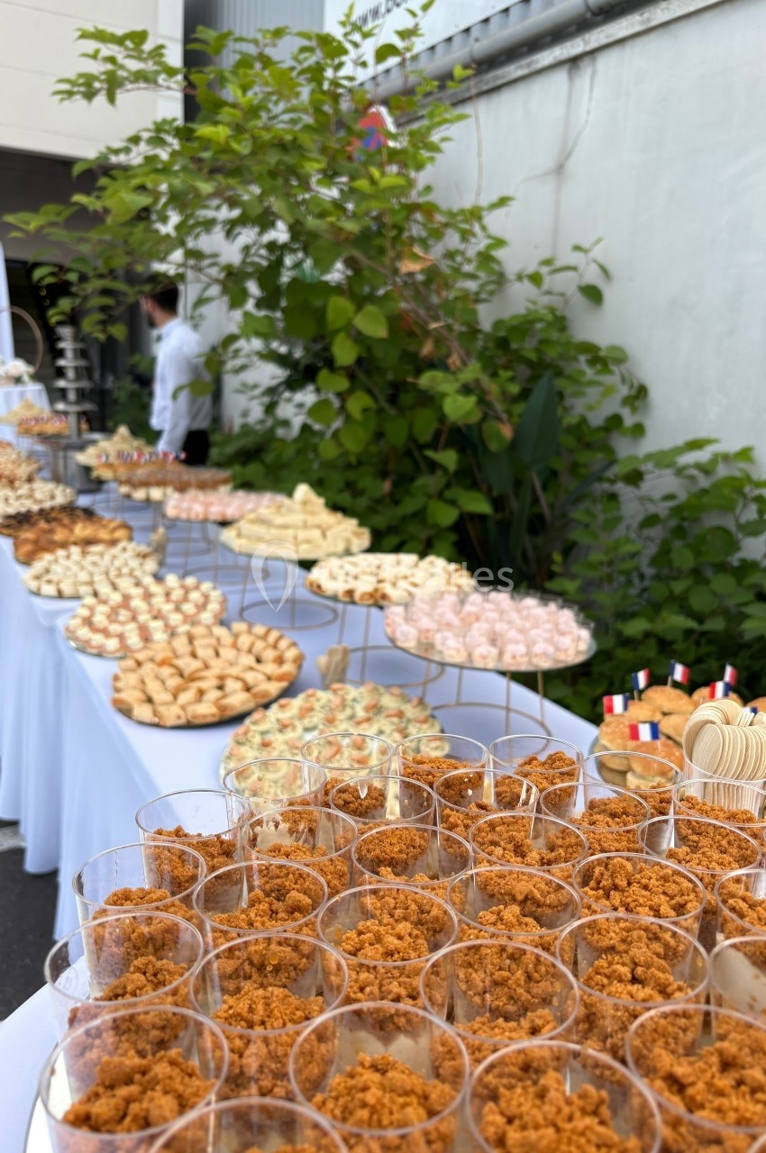 Buffet en extérieur avec une variété de desserts et amuse-bouches disposés sur des tables alignées.