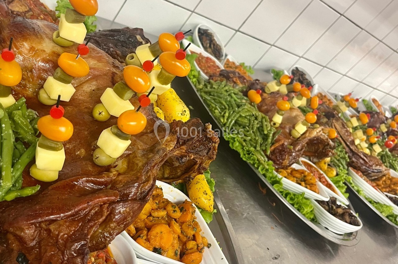 Plateaux garnis de viandes rôties, légumes variés, brochettes de fromage et tomates cerises dans une cuisine professionnelle.