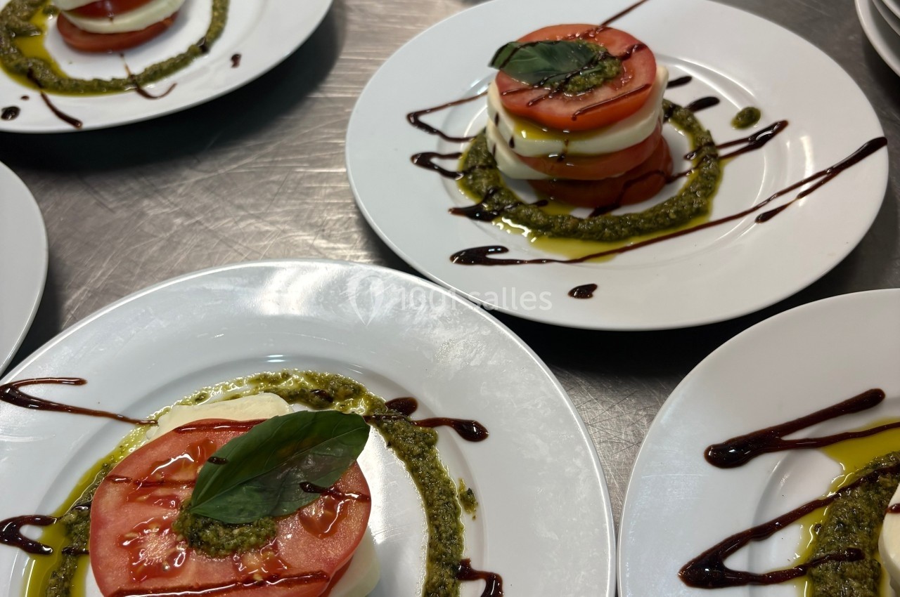 Assiettes de salade caprese avec tomates, mozzarella, pesto, filet de balsamique et feuille de basilic.